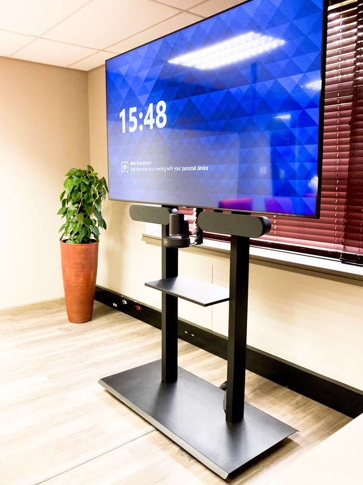 75inch UHD room display in front of the windows using a floor-standing bracket with a Logitech Rally Plus